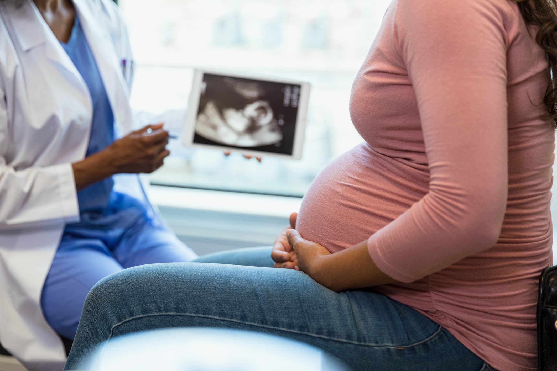 Pregnant woman looking at ultrasound of baby in doctor's office.