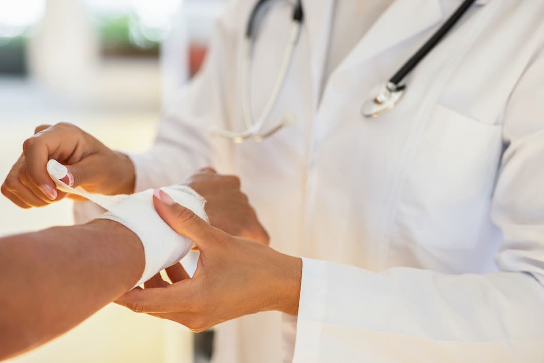 Doctor wrapping a wound on patient.